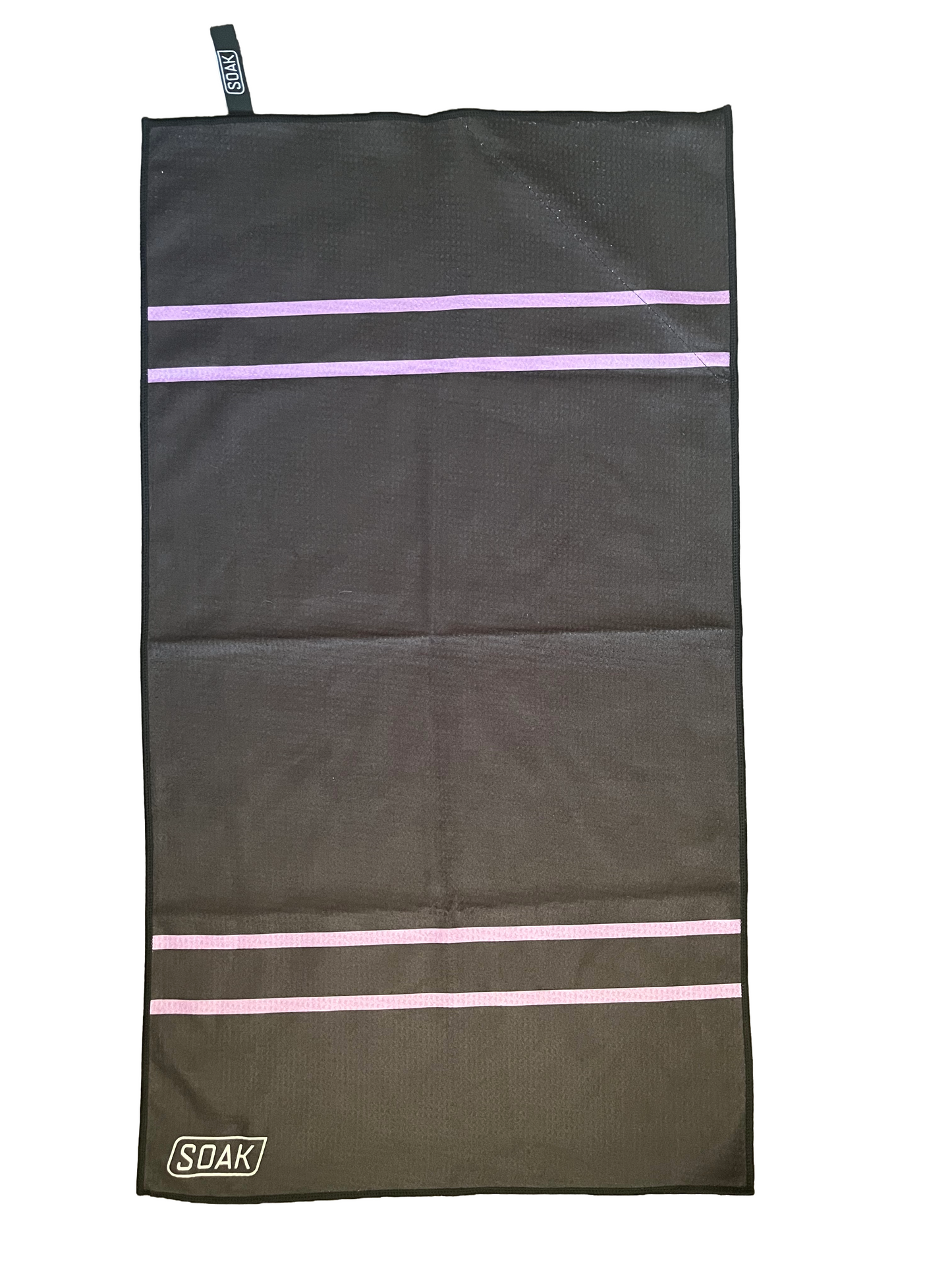 Black towel with lilac stripes and SOAK branding plus large zip pocket and hanging loop.